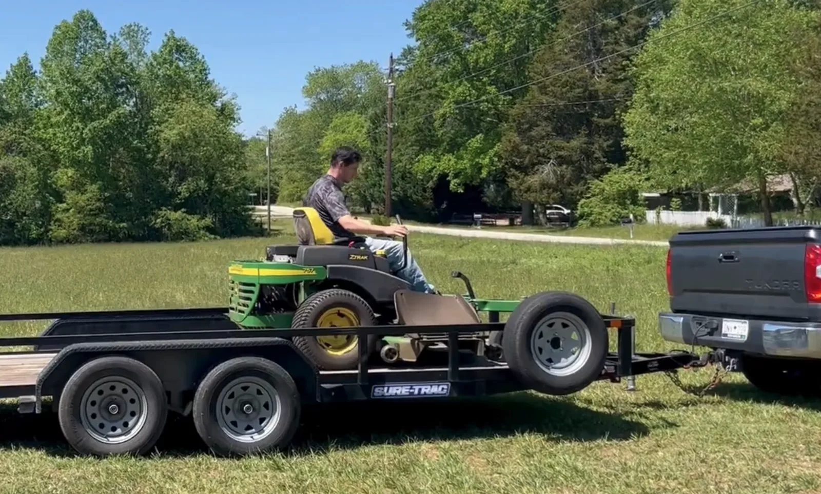 man driving mower onto trailer